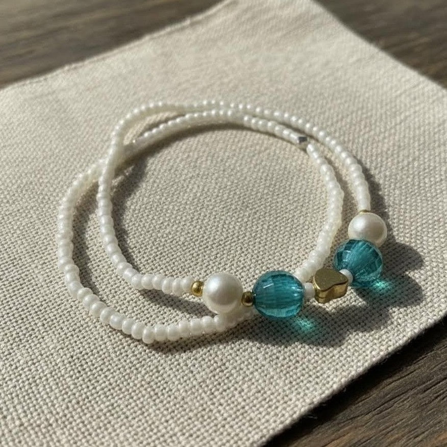 Beaded bracelet with pearls and blue beads on a textured surface