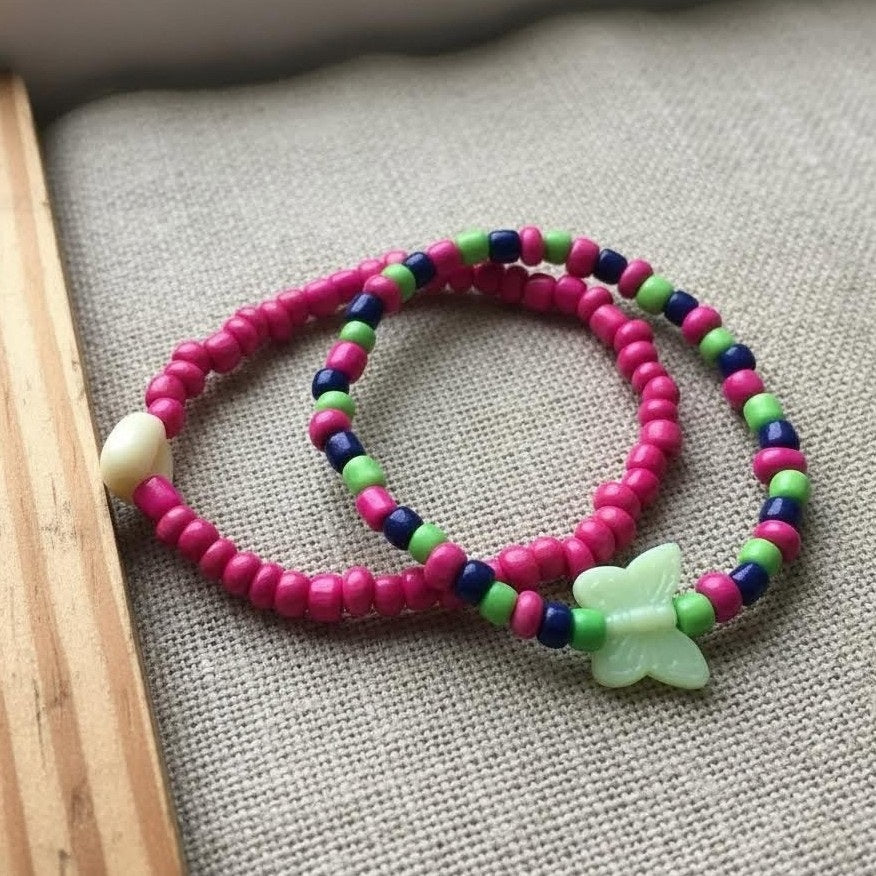 Colorful beaded bracelet with a butterfly charm on a textured surface