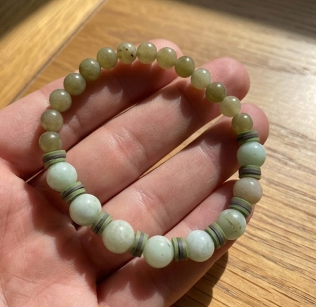 Hand holding a beaded bracelet on a wooden surface