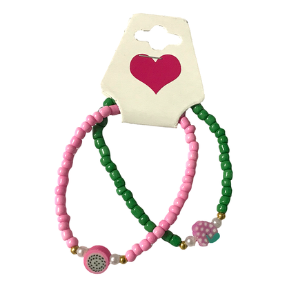 Two beaded bracelets, one pink and one green, on a card with a heart design.