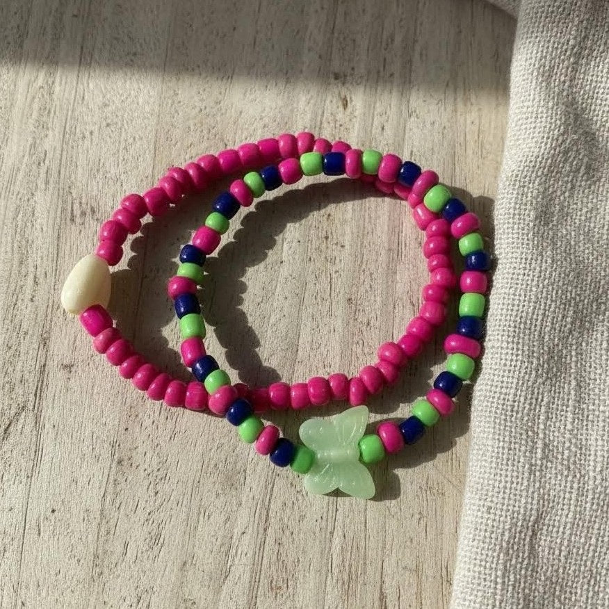 Colorful beaded bracelet with a butterfly charm on a wooden surface