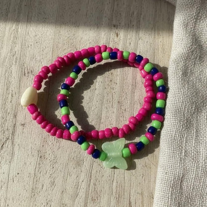 Colorful beaded bracelet with a butterfly charm on a wooden surface
