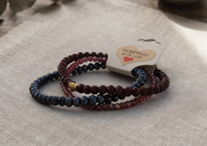 Set of beaded bracelets on a textured surface with a 'Handmade with Love' tag.