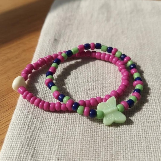 Colorful beaded bracelet with a butterfly charm on a textured fabric surface.