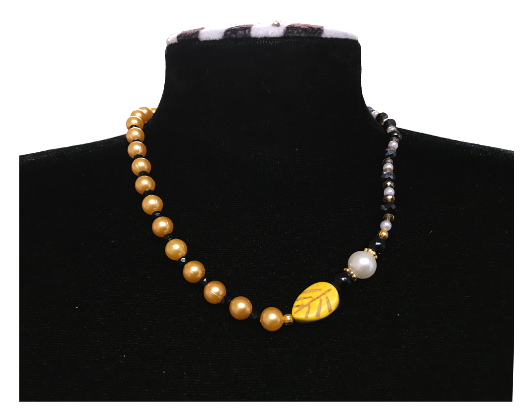 Necklace with gold and black beads on a black mannequin bust