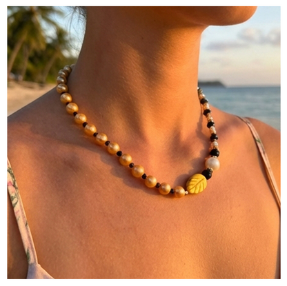 Necklace with leaf-shaped beads worn by a person with a beach background