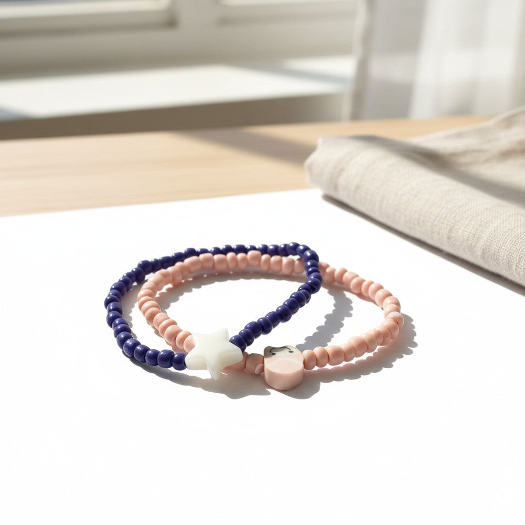 Two beaded bracelets, one pink and one blue, on a light surface with a blurred background.