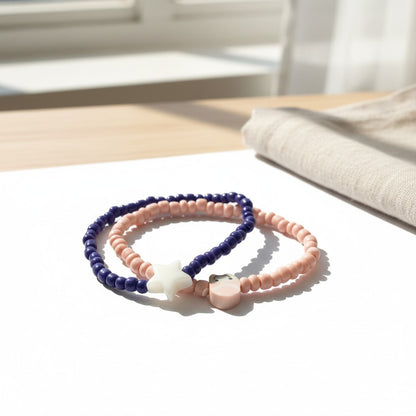 Two beaded bracelets, one pink and one blue, on a light surface with a blurred background.