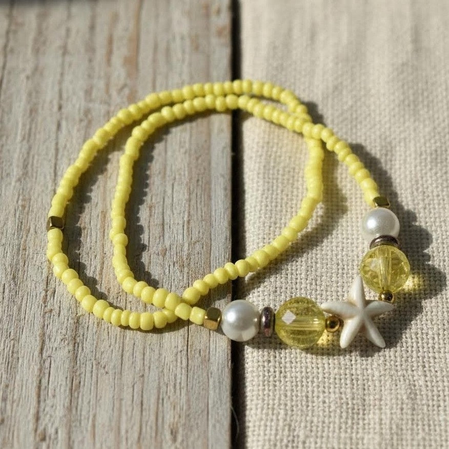 Yellow beaded bracelet with starfish charm on a wooden surface