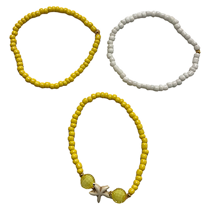 Three beaded bracelets, two yellow and one with a starfish charm, on a white background.