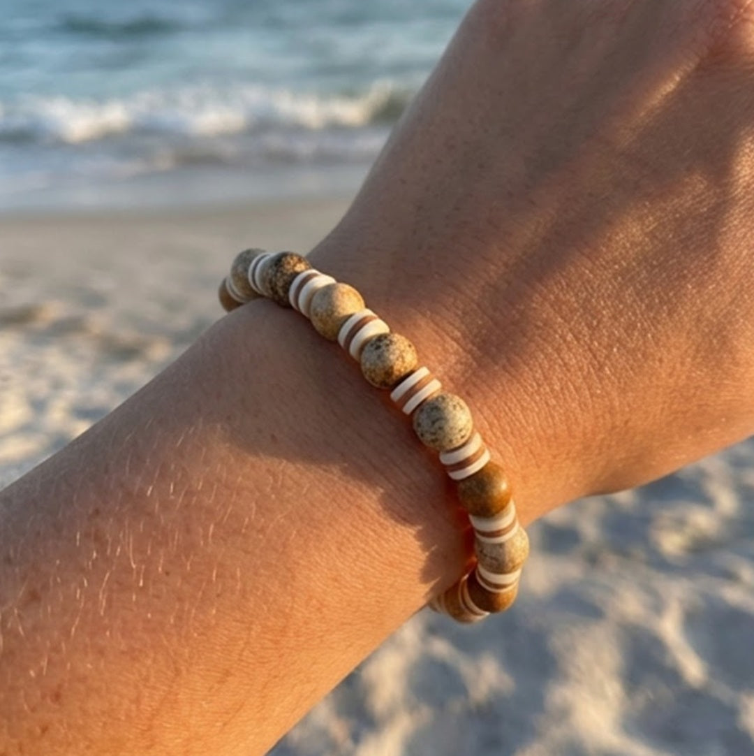 Light brown beaded bracelet on a wrist with a beach background