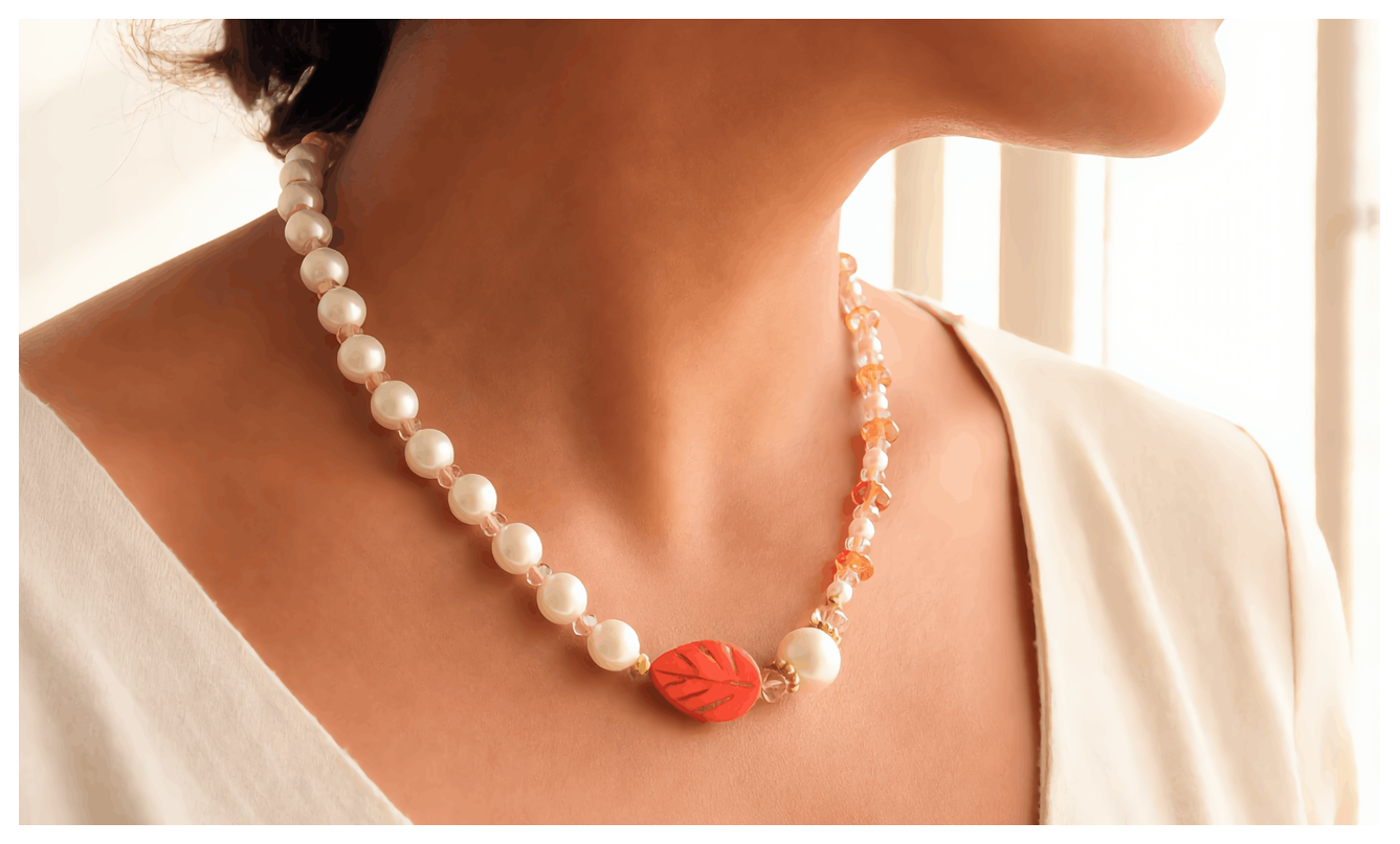 Pearl necklace with a red leaf pendant on a person wearing a white top.