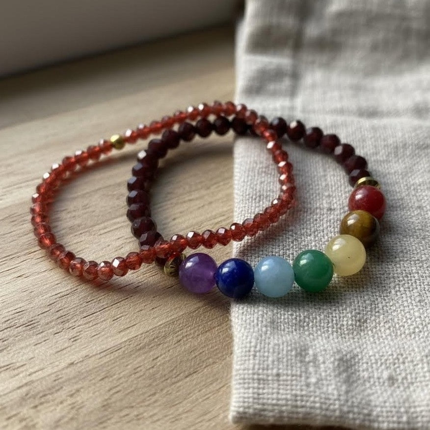 Two beaded bracelets on a wooden surface with a fabric background