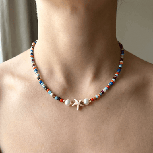 Handmade Beaded Multicolor Necklace with Starfish Charm and Faux Pearls on a woman's neck