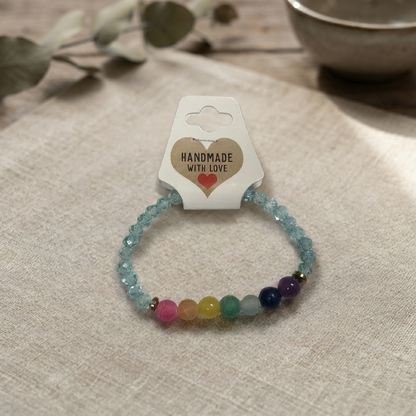 Multicolored beaded bracelet on a beige surface with a 'Handmade with Love' card.