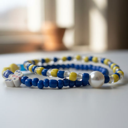 Two beaded bracelets with blue, yellow, and white beads on a light surface.