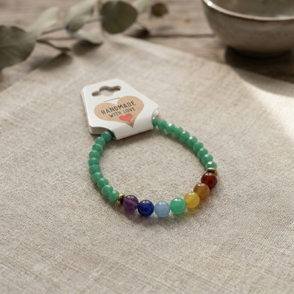Beaded bracelet with multicolor and green stones on a beige fabric background