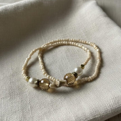 Beaded bracelet with white and brown beads on a light fabric background