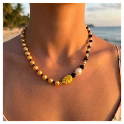 Necklace with leaf-shaped beads on a person against a beach background