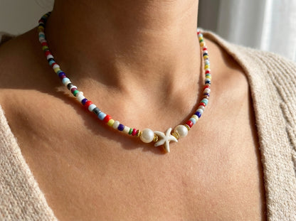 Colorful beaded necklace with a starfish pendant on a person wearing a beige top.