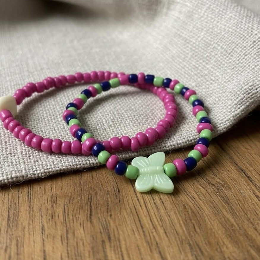 Colorful beaded bracelets with a butterfly charm on a textured fabric background