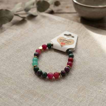 Multicolored beaded bracelet on a beige fabric surface with a 'Handmade with Love' tag.