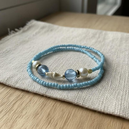 Blue beaded bracelet with white pearls on a textured surface