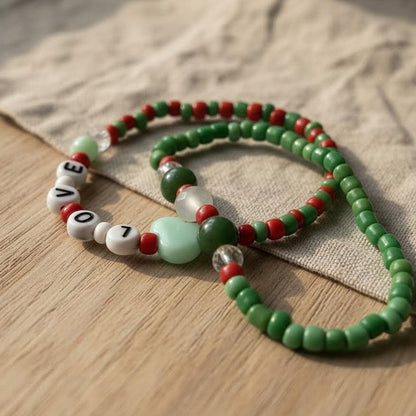 Green and red beaded necklace with letter beads on a wooden surface