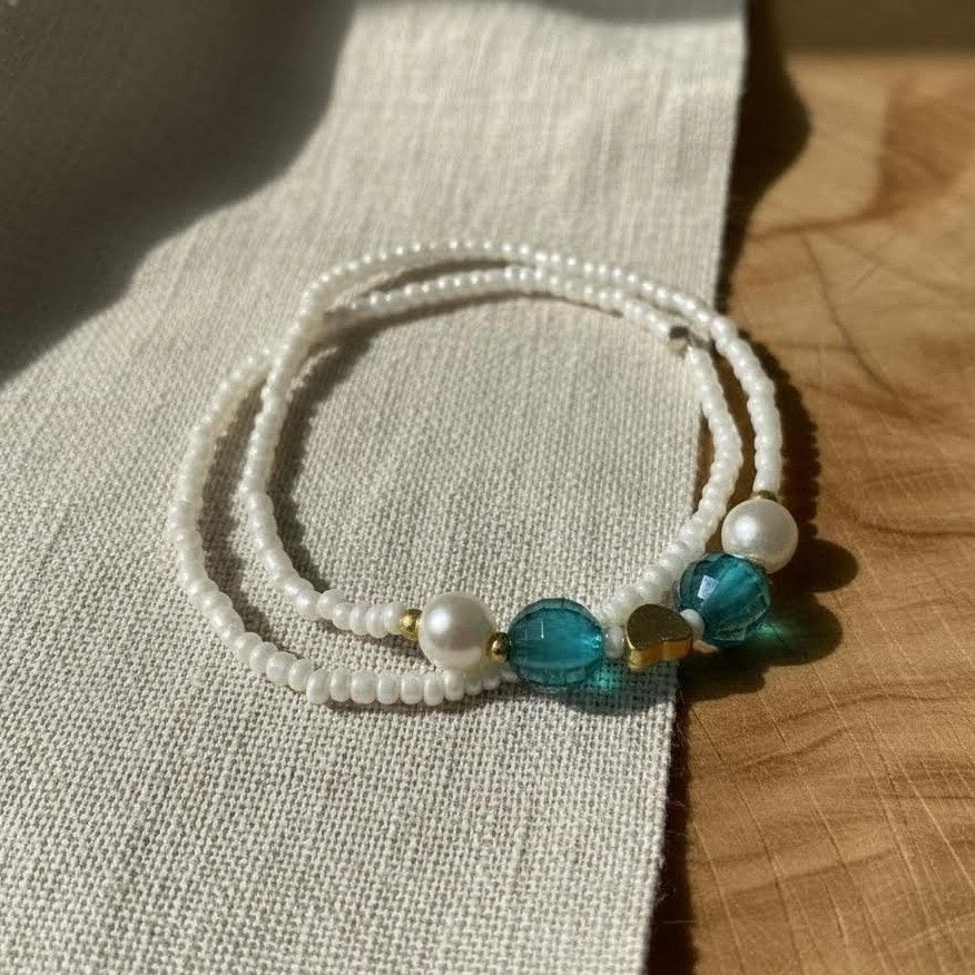 Beaded bracelet with pearls and blue beads on a textured fabric background