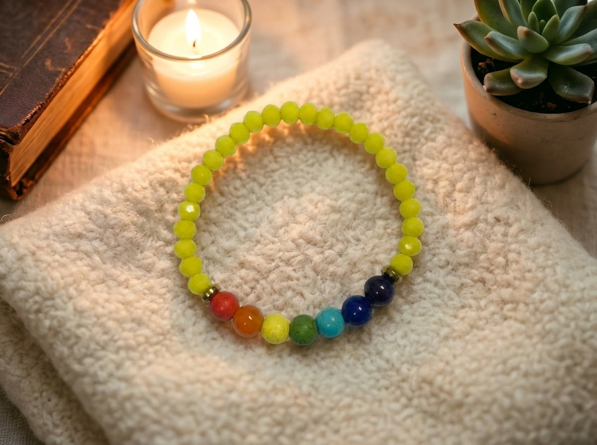 Colorful beaded bracelet on a textured surface with a candle and plant in the background