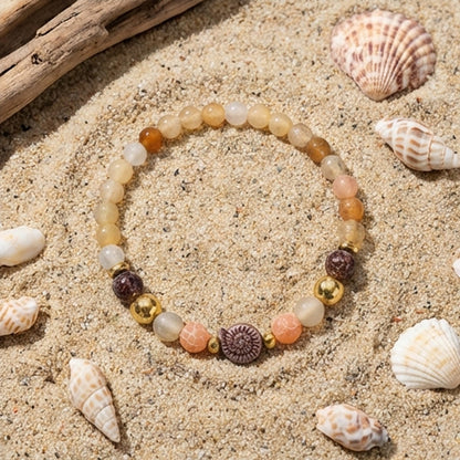 Beaded bracelet on sand with seashells