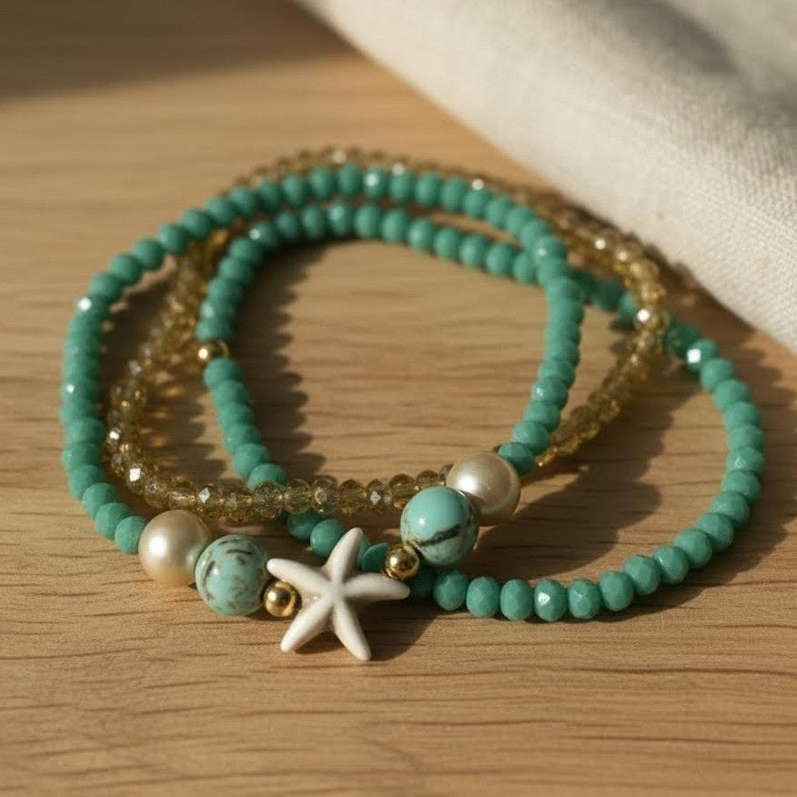 Set of turquoise beaded bracelets with starfish charm on a wooden surface
