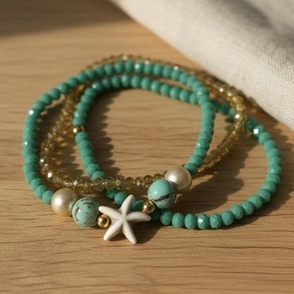 Set of turquoise beaded bracelets with starfish charm on a wooden surface