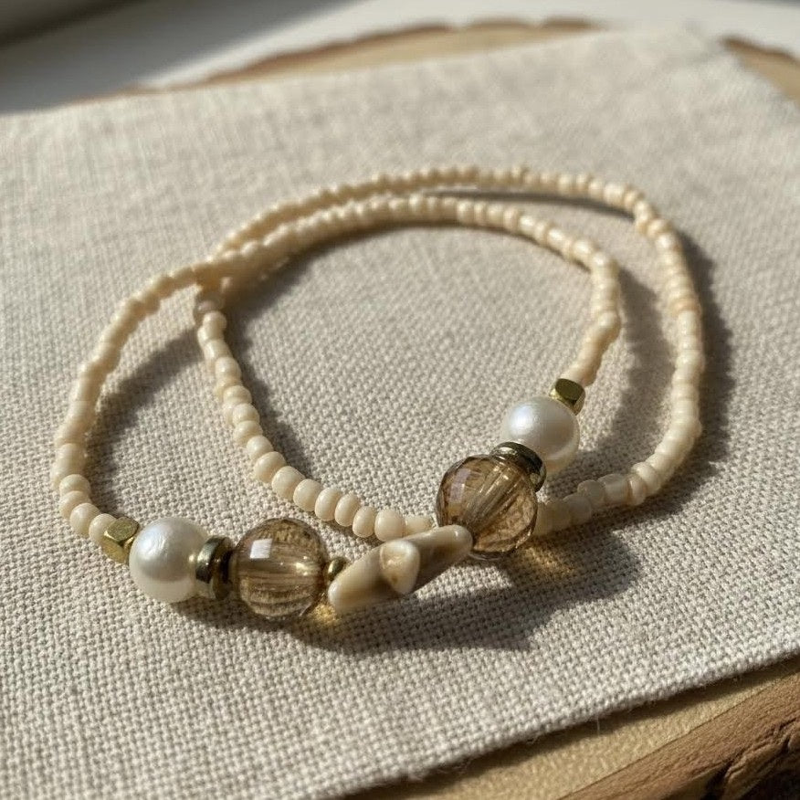 Beaded necklace with white and brown beads on a textured fabric surface