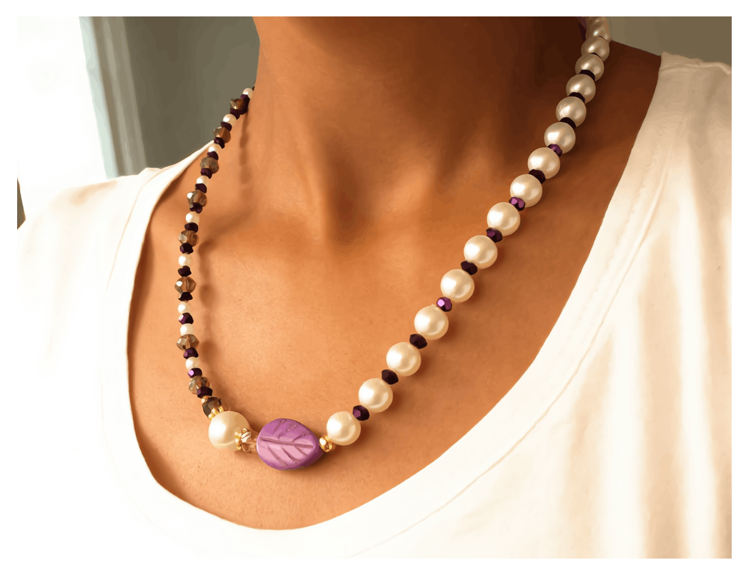 Necklace with white pearls and purple leaf pendant on a person wearing a white shirt.