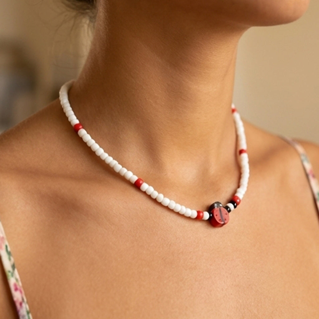 Close-up of a person wearing a red and white beaded necklace with a blurred background