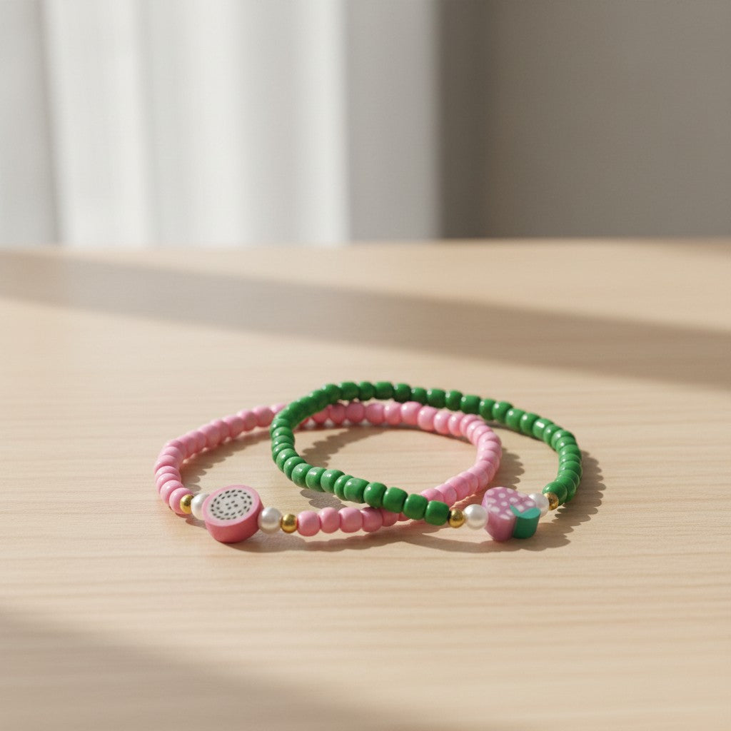 Two beaded bracelets, one pink and one green, on a light surface with a neutral background.