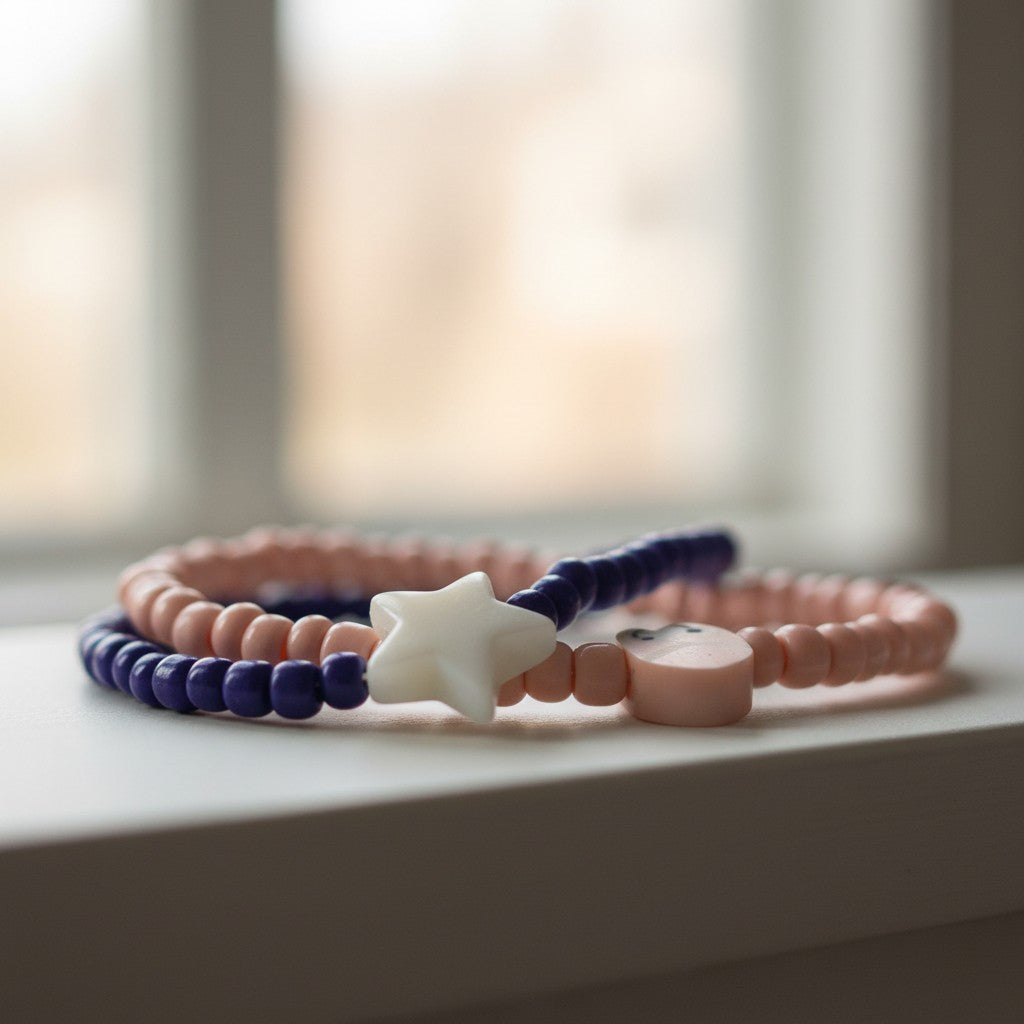 Three beaded bracelets with star and heart charms on a light surface with a blurred window background.