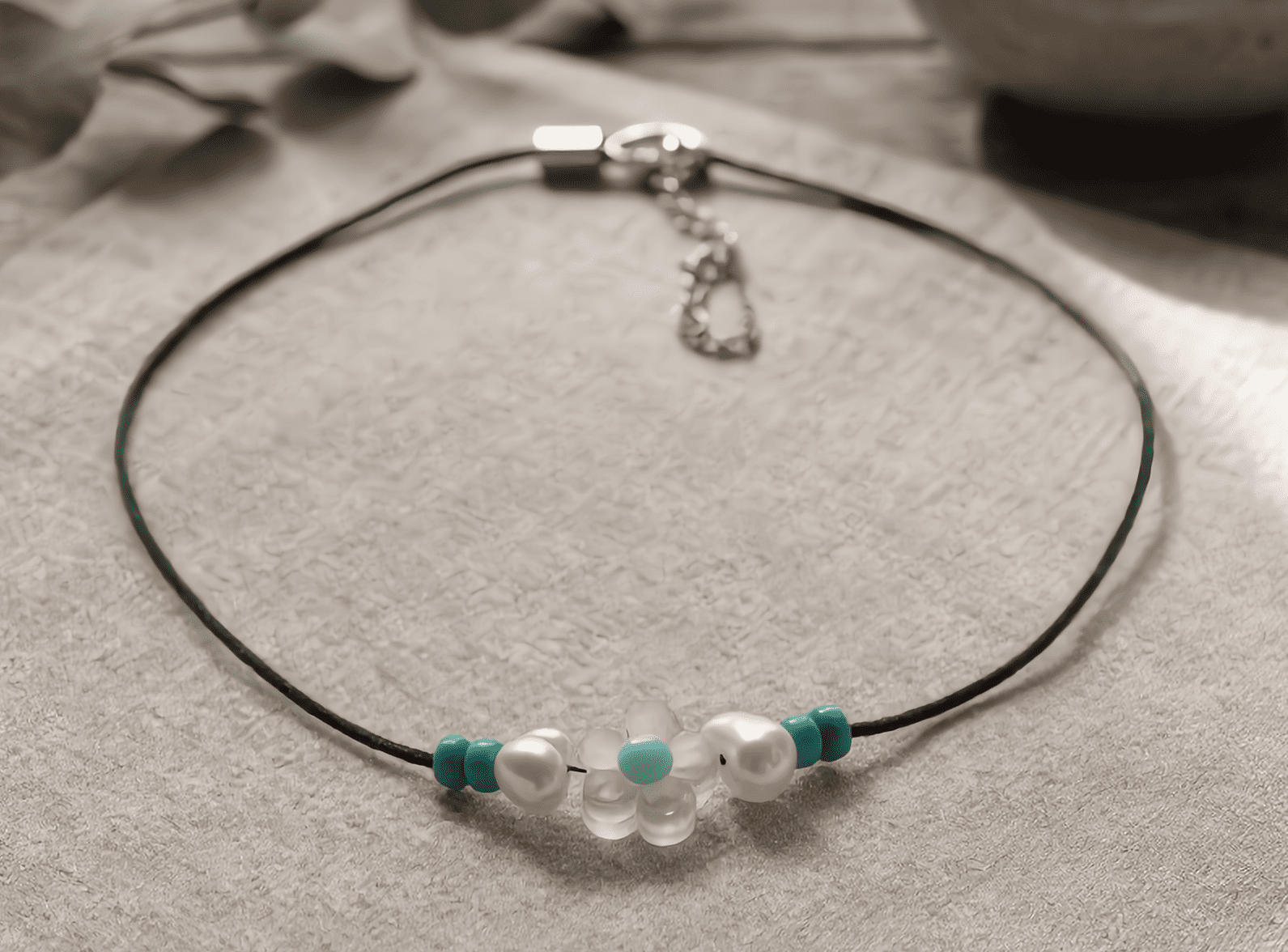 Necklace with pearls and green accents on a textured surface