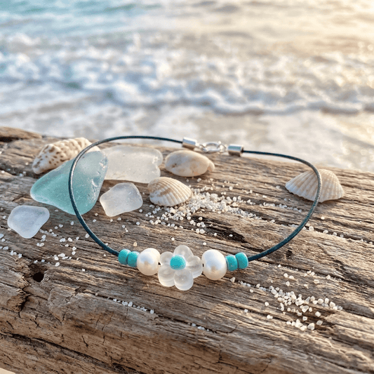 Necklace with floral beads on a wooden surface near the ocean