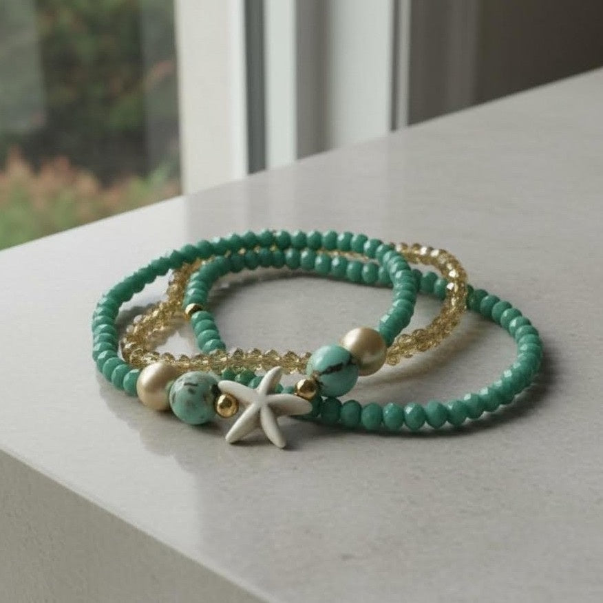 Turquoise beaded bracelet with gold accents and a starfish charm on a light surface.