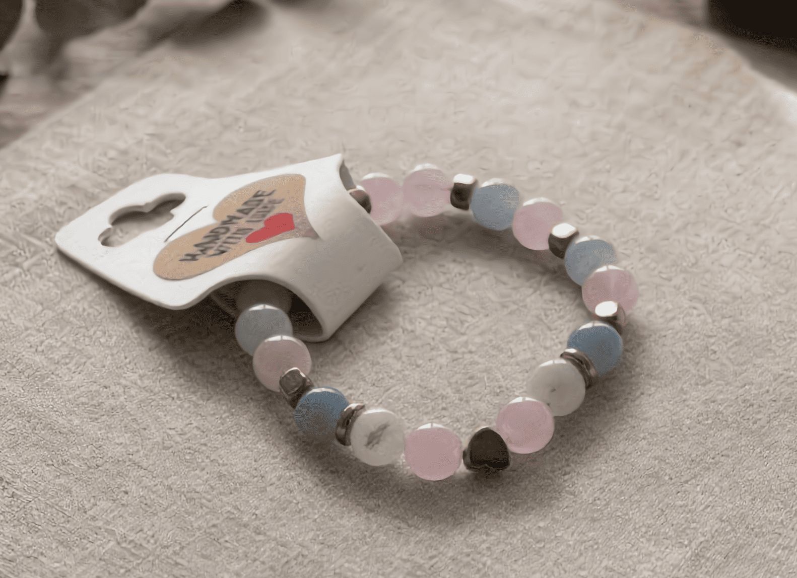 Beaded bracelet with heart-shaped tag on a beige surface