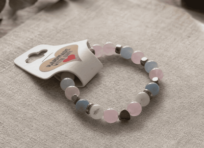 Beaded bracelet with heart-shaped tag on a beige surface