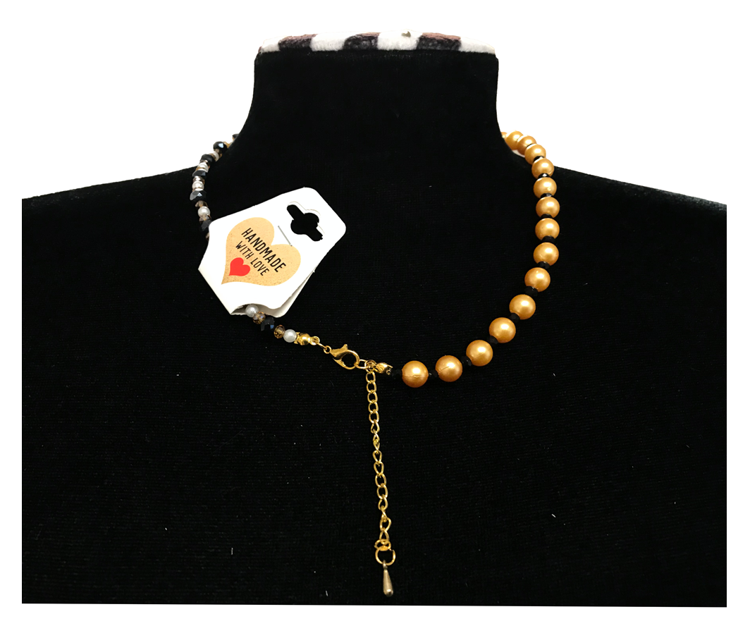 Gold necklace with a key pendant on a black stand with a visible brand tag.