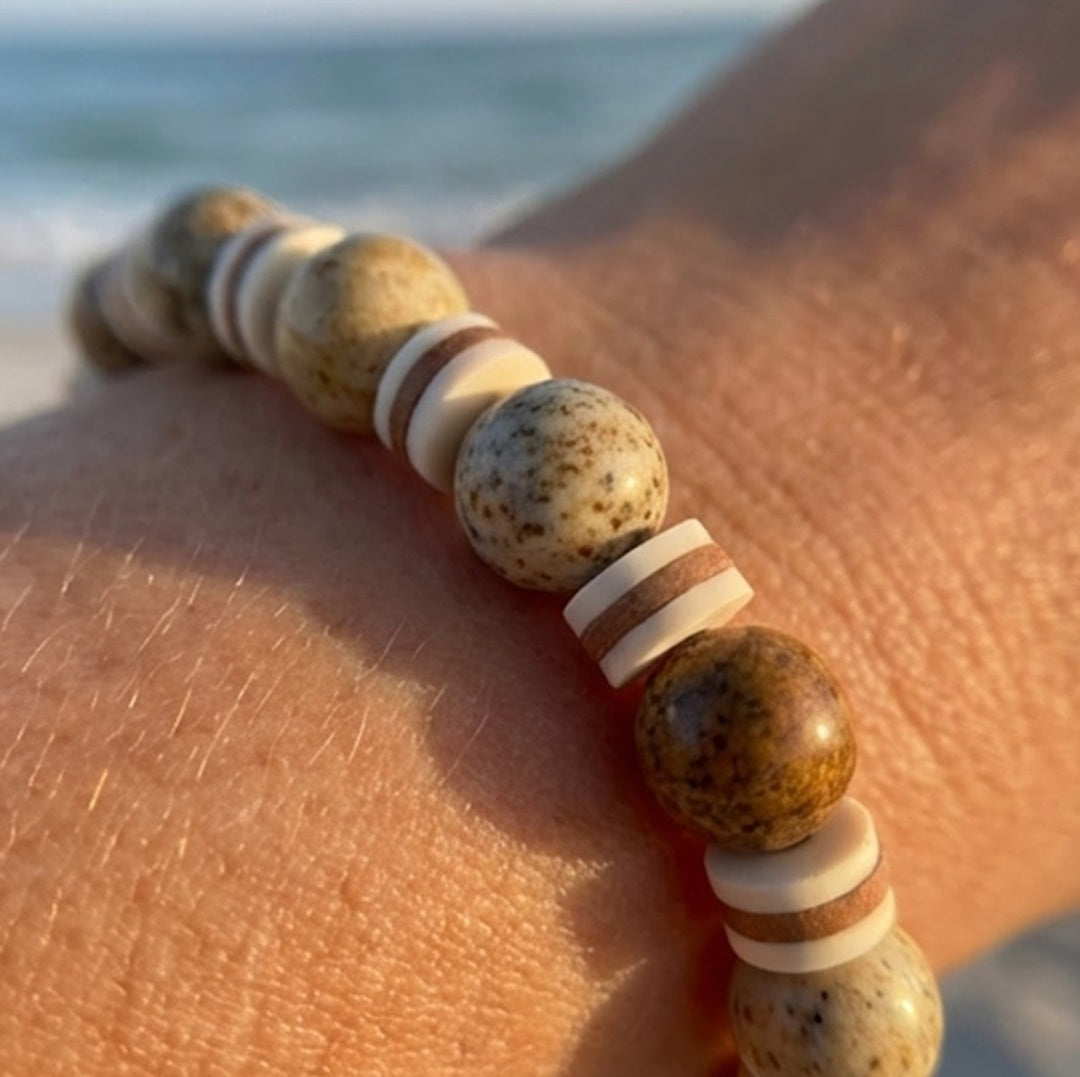 Beaded bracelet with natural stones on a person's wrist by the sea.