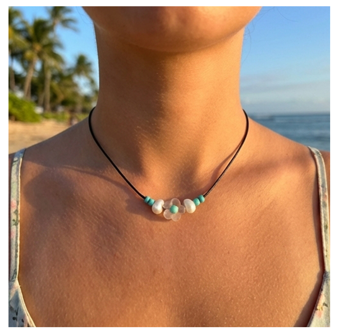 Necklace with turquoise and white beads worn by a person on a beach.