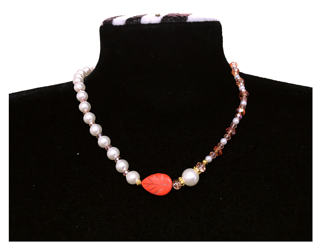 Necklace with pearls and a red leaf-shaped bead on a black mannequin.