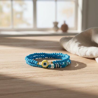 Blue beaded bracelet with a yellow evil eye charm on a wooden surface.