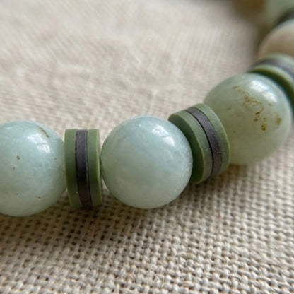 Close-up of a green beaded bracelet on a textured fabric background