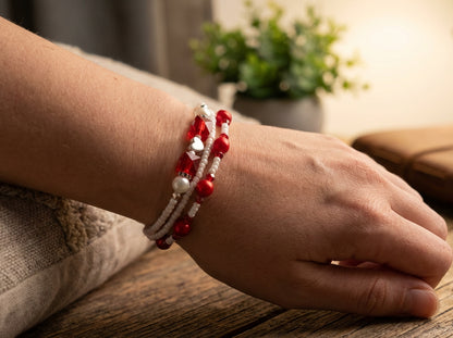 Close-up of a wrist wearing a red and white beaded bracelet on a wooden surface.